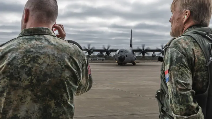 Hercules op de grond met links een militair op de rug en rechts de koning, eveneens in uniform. 