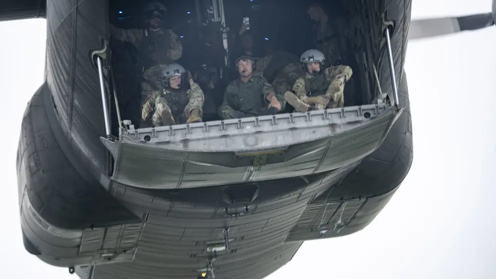 Parachutisten zitten klaar om uit het vliegtuig te springen. In het midden de koning. 