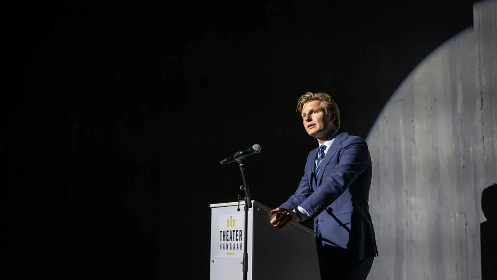 Minister Ruben Brekelmans tegen donkere achtergrond achter katheder.