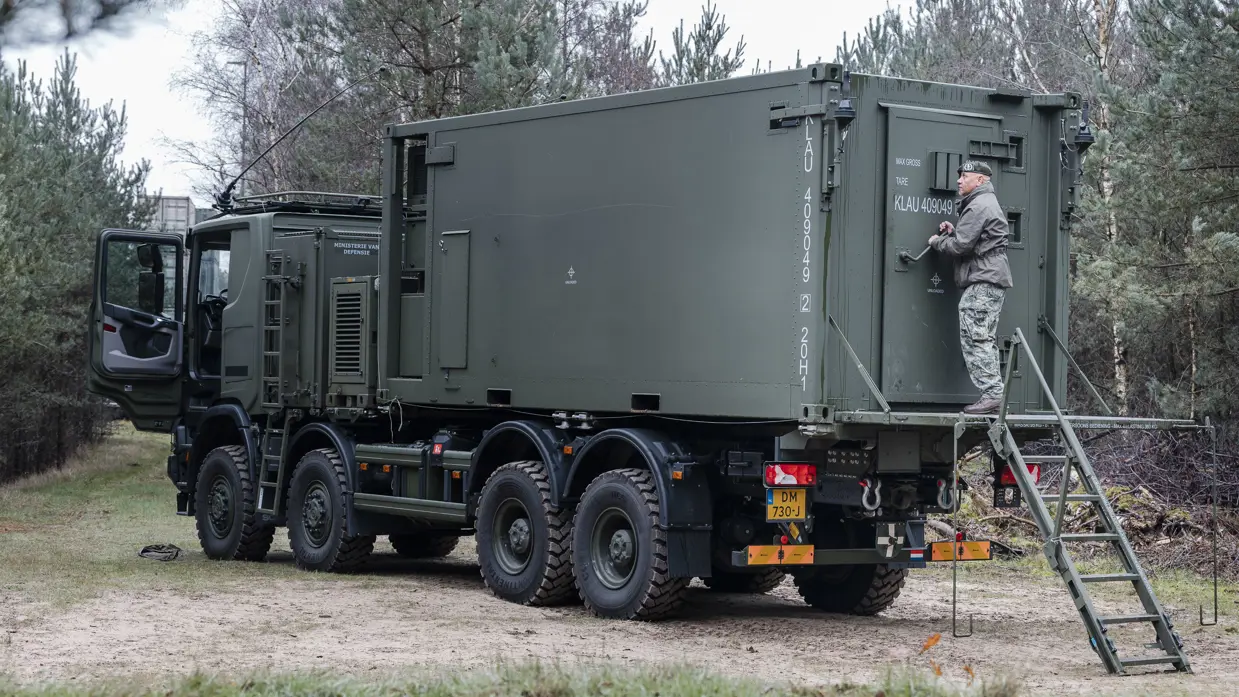 Militair achterop een stilstaande truck.