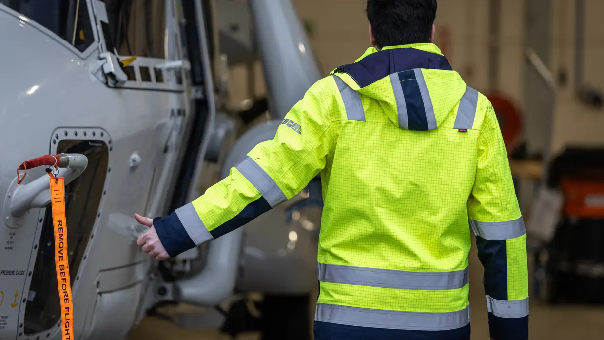 Een NH90 wordt met een speciaal voertuig uit een hangar getrokken.