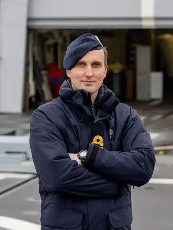 De squadroncommandant in uniform met de handen voor de borst.
