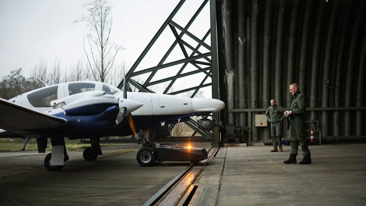 Diamond DA62 MPP-patrouillevliegtuig wordt met een grondvoertuig uit de hangar gehaald.