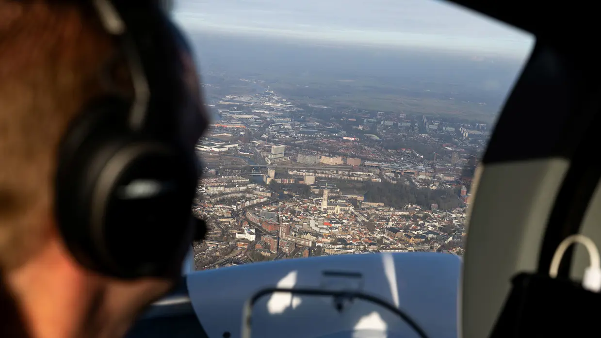 Uitzicht vanuit de cockpit van het patrouillevliegtuig op een stedelijk gebied tijdens een vlucht.