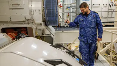 Korporaal TD Guus van Rensen schijnt met een zaklamp in een deel van de motor. Daarnaast een portretfoto van hem.