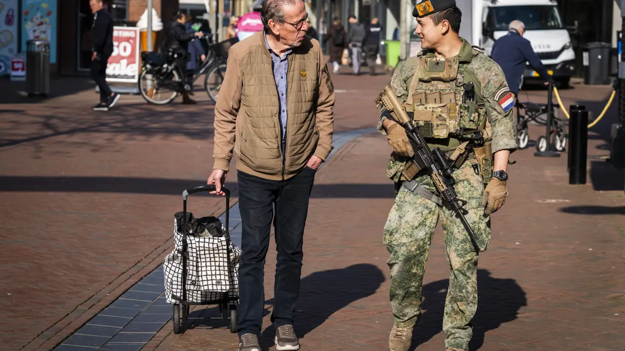 Een militair en een burger in gesprek in de stad.