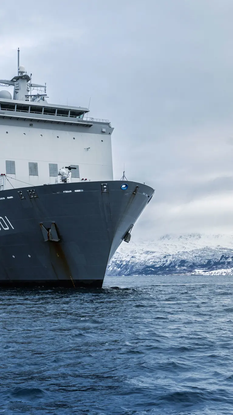 Zr.Ms. Johan de Witt vaart langs een besneeuwde Noorse kust tijdens oefening Cold Response. 