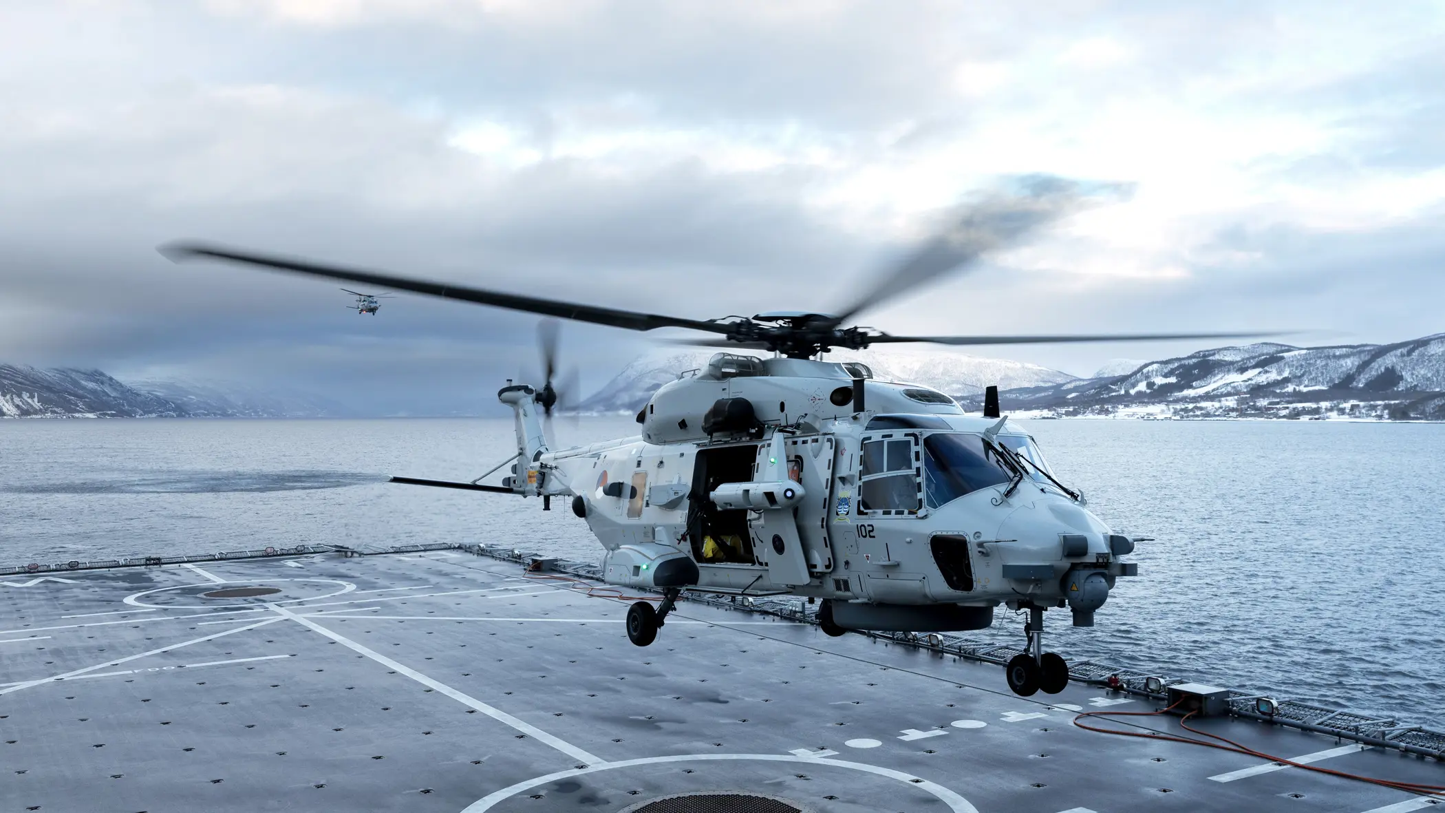 Een NH90 landt op het helikopterdek van een schip.