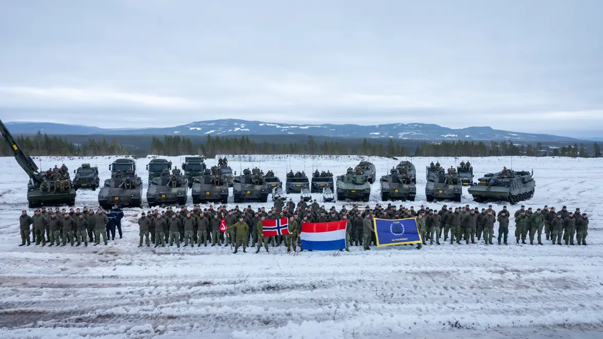 Groepsfoto van de Charlie-compagnie en de Noorse instructeurs voor alle voertuigen in een winters landschap.