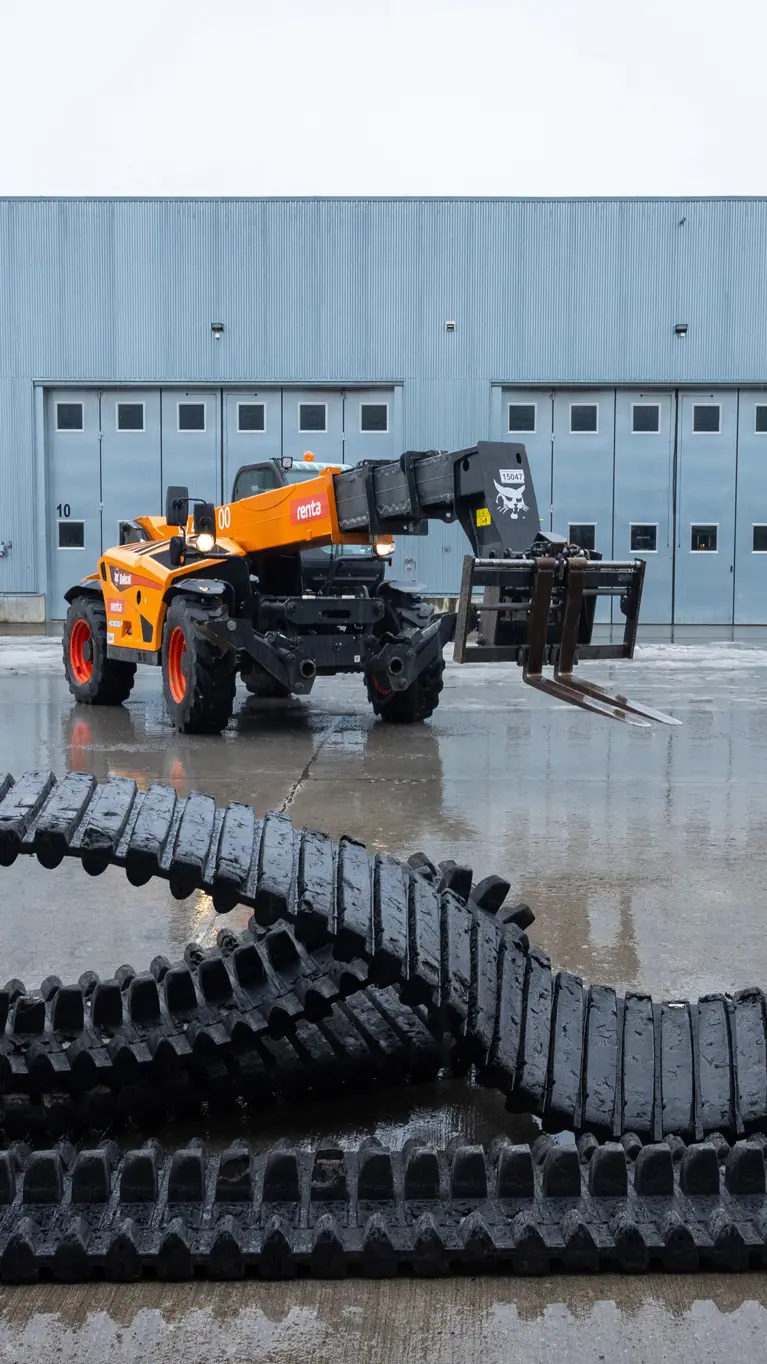 Een grote rubberen band ligt op de grond, erachter staat een kraanwagen. 