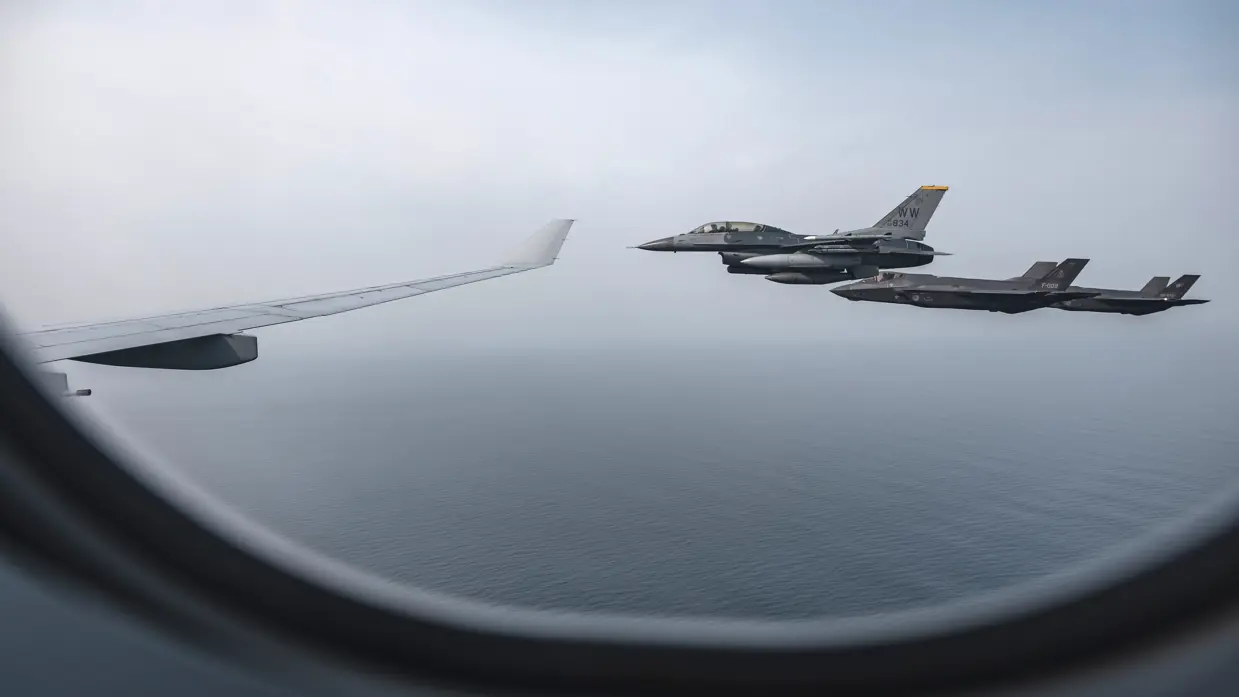 Beeld uit een raampje van een A330 MRRT. Te zien zijn de rechtervleugel van het toestel met daarnaast een Amerikaanse F-16 en een Nederlandse en Japanse F-35.