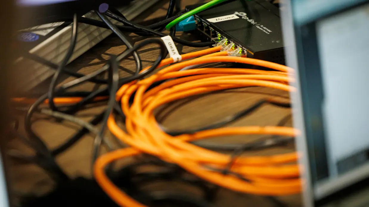  Verschillende gekleurde kabels die over een tafel naar een modem toelopen.