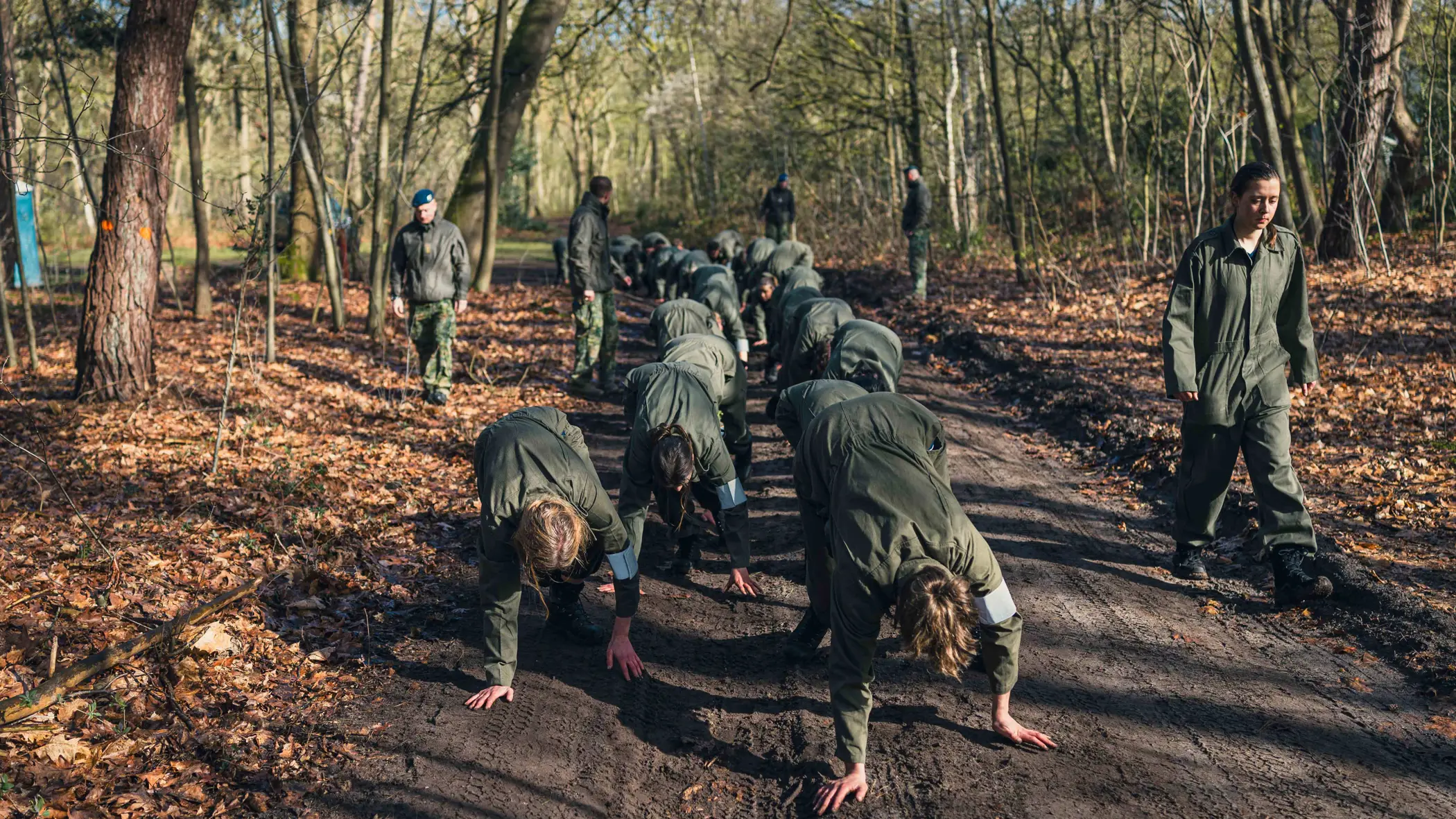 Militairen tijgeren onder begeleiding over een bospad.