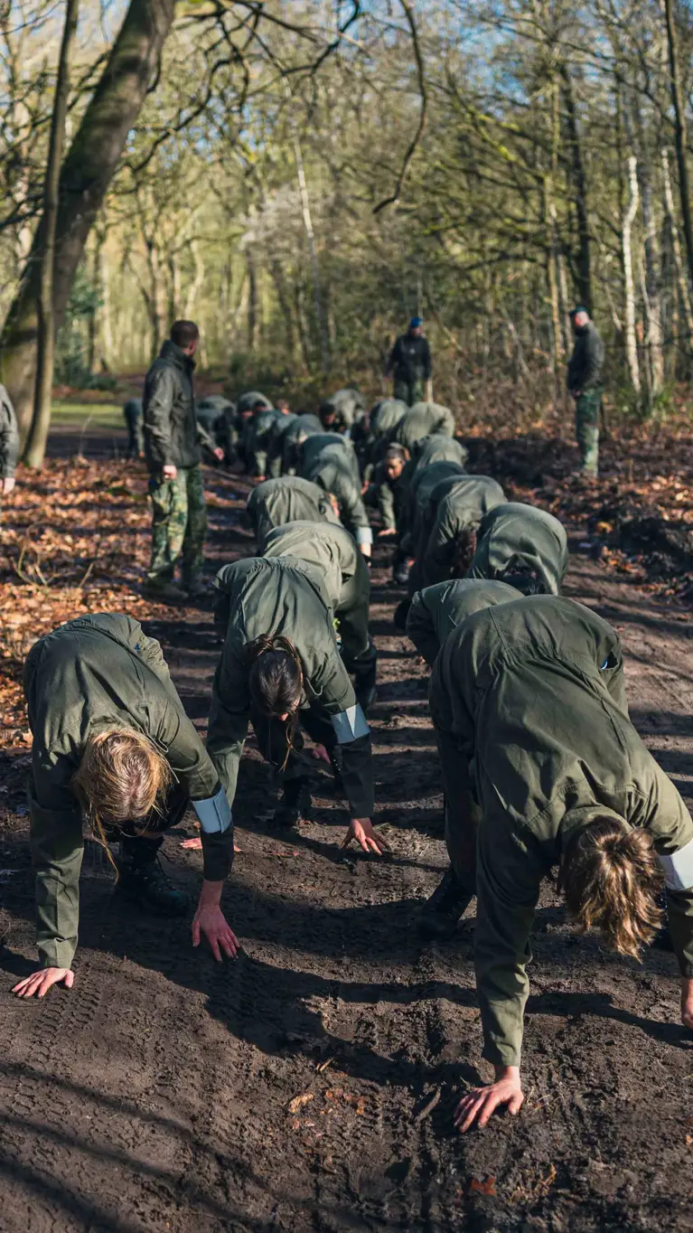 Militairen tijgeren onder begeleiding over een bospad.