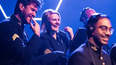 Musici van het Orkest Koninklijke Luchtmacht lachen samen tijdens het concert.