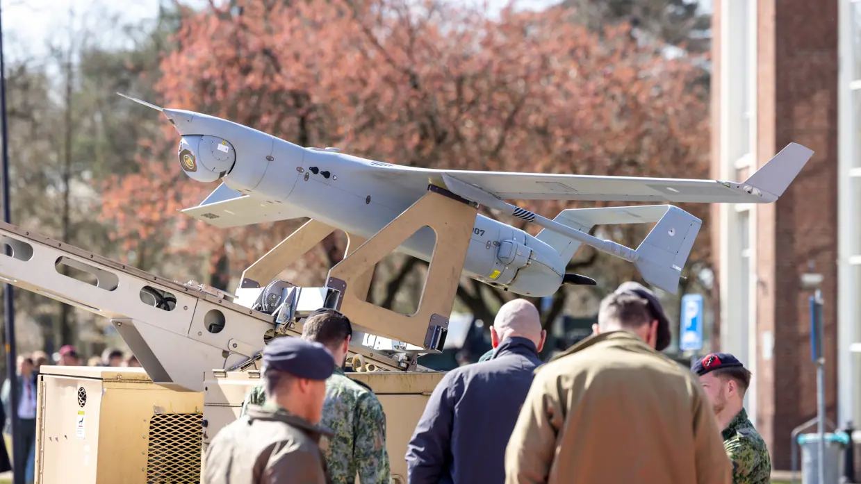 Militairen en bezoekers bekijken een drone tijdens een demonstratie.