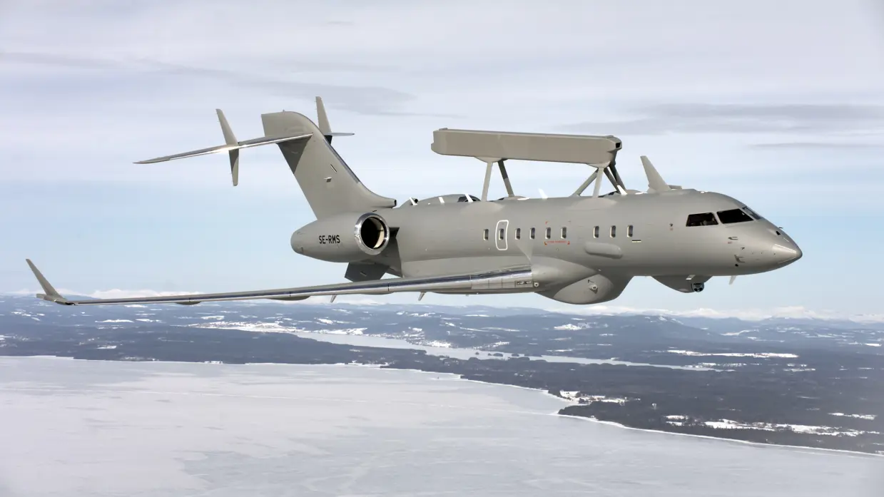 Een grijze GlobalEye vliegt boven een besneeuwde omgeving.