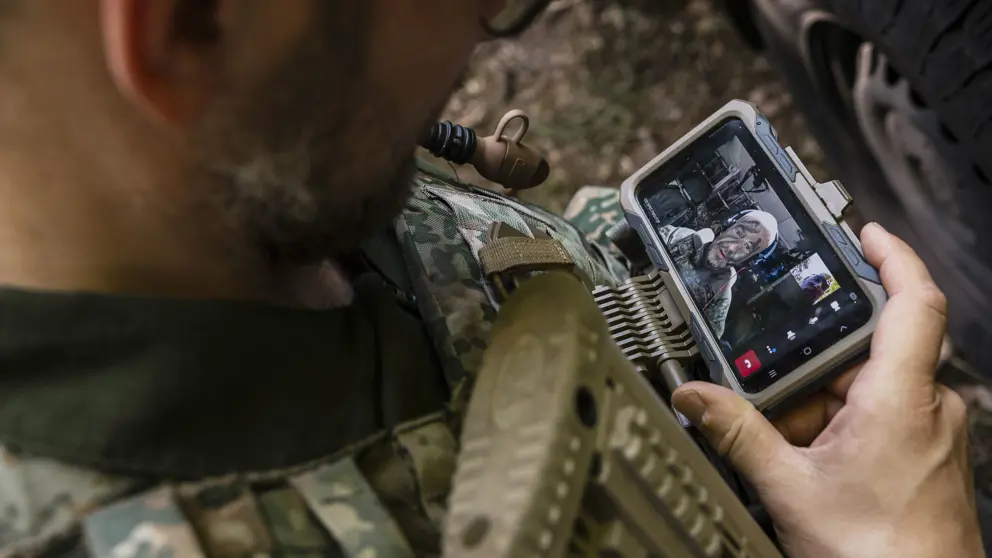 Een militair te velde werkt op een mobiel device.