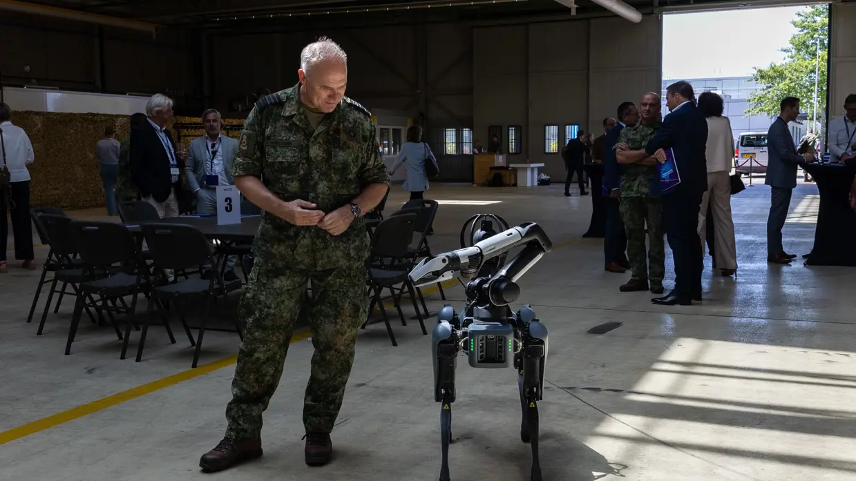 Commandant der Strijdkrachten Eichelsheim kijkt naar een robot. 