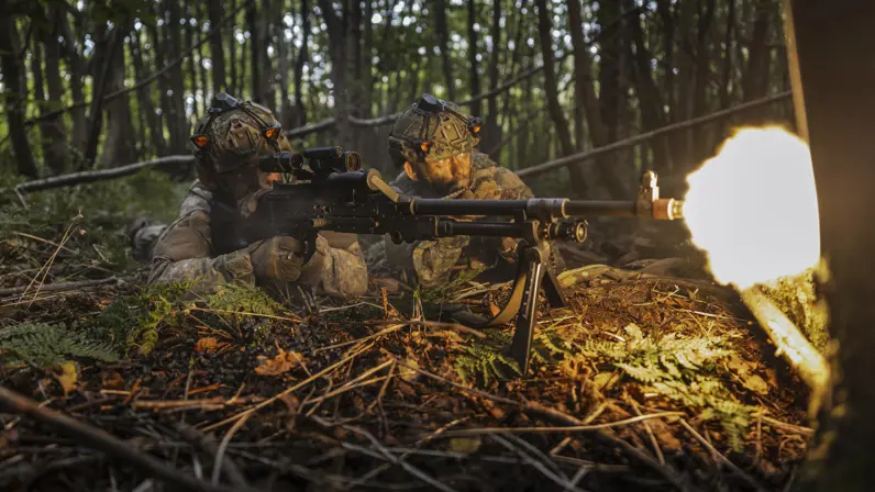 Een militair vuurt liggend zijn mitrailleur.