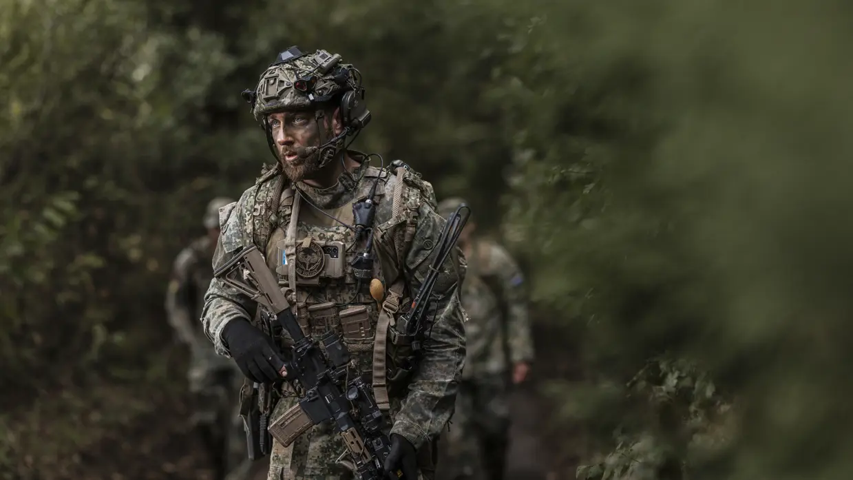 Een militair loopt door het bos en scant de omgeving.