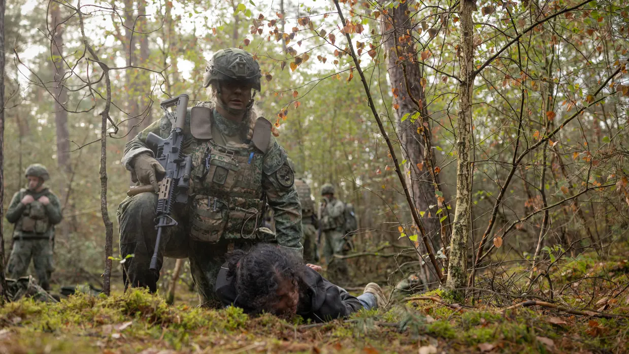 Militair in bos houdt persoon staande.