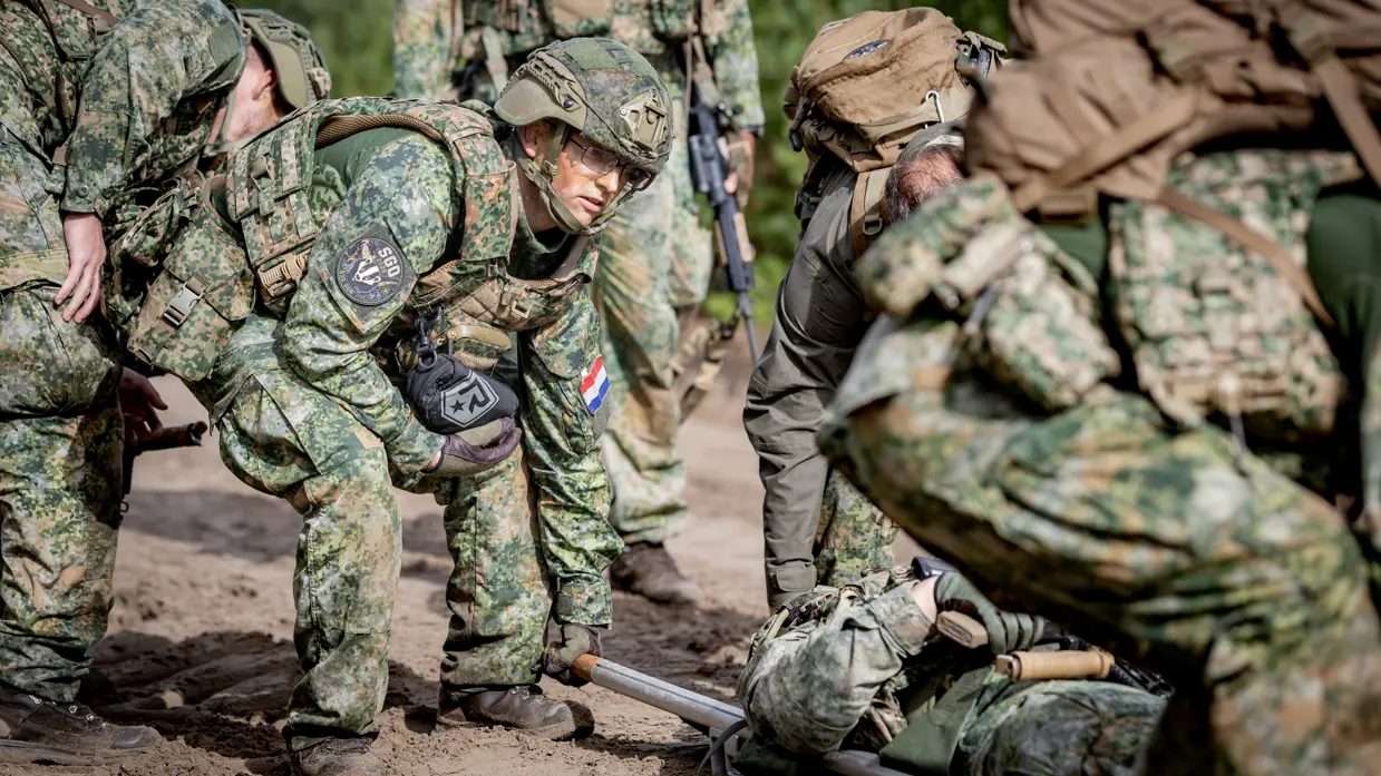 Militairen tillen brancard op.