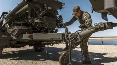 Een militair ontkoppelt een aanhanger met daarop een antenne-installatie.
