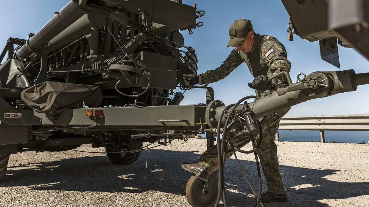 Een militair ontkoppelt een aanhanger met daarop een antenne-installatie.