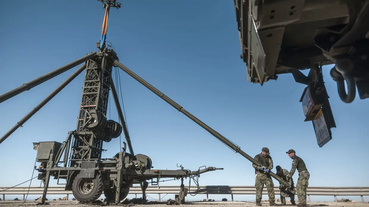 Militairen leggen de laatste hand aan het stabiliseren van een lange antennemast.