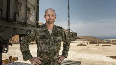 Portretfoto van commandant Stuart Lorraine met een antennemast in de achtergrond.