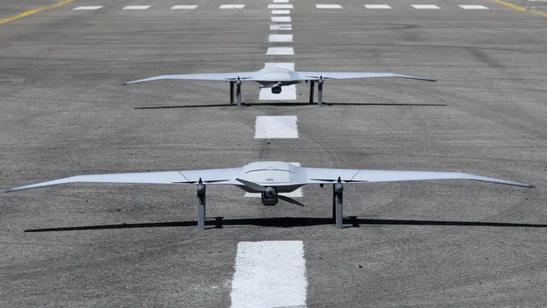  2 drones staan achter elkaar op een landingsbaan.