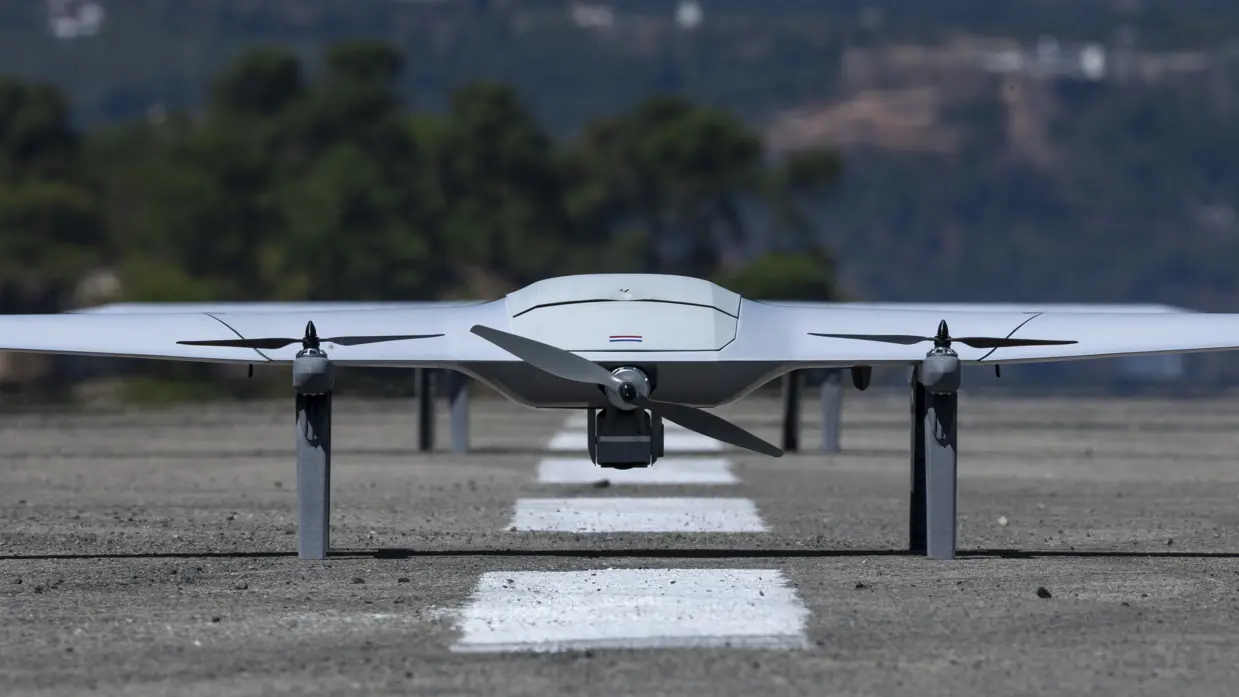 Een grijze drone met daarop een Nederlands vlaggetje op een start- en landingsbaan. 