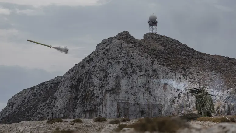 Militairen in een zogeheten ghillie suit (bijzonder soort camouflagepak) schieten een Stinger-luchtdoelraket in een landschap vol rotsen.