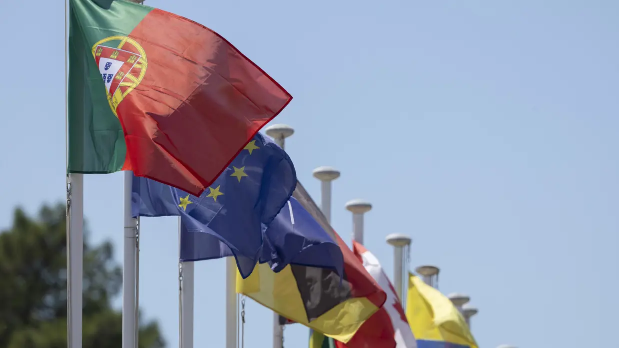 Een rij met wapperende vlaggen. Vooraan die van Portugal.