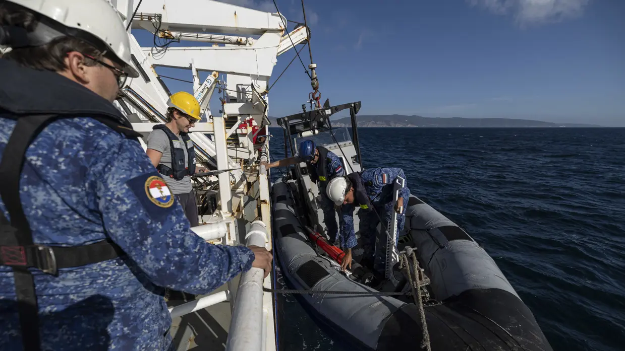 Een RHIB hangt aan de zijkant van een schip. 