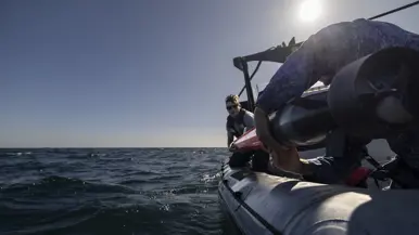 Een vrouw en een man in uniform laten een oranjekleurige torpedo te water vanaf de RHIB. 