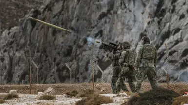 Drie militairen in vol ornaat zijn betrokken bij de lancering van een Stinger-luchtdoelraket.