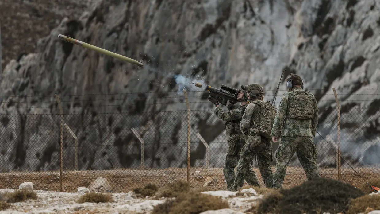 Drie militairen in vol ornaat zijn betrokken bij de lancering van een Stinger-luchtdoelraket.