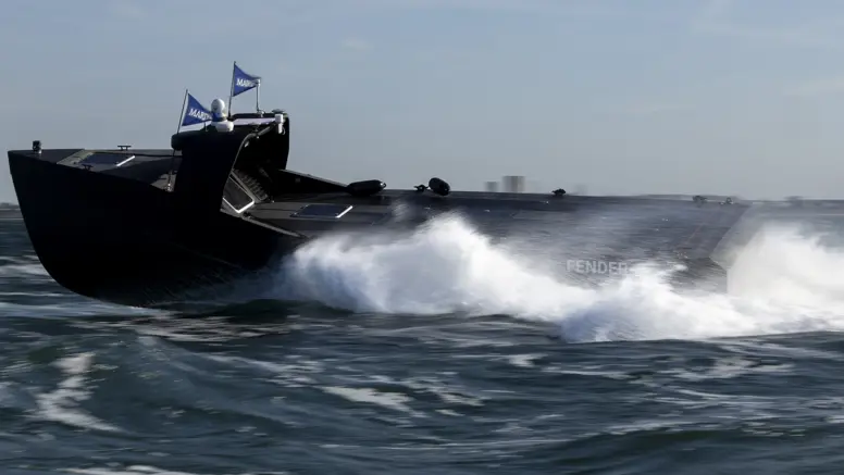 Een zwart, onbemand bootje scheurt over het water en laat daarbij golven achter.