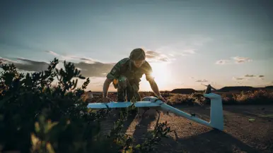 Een militair zit geknield en zet een drone in elkaar.