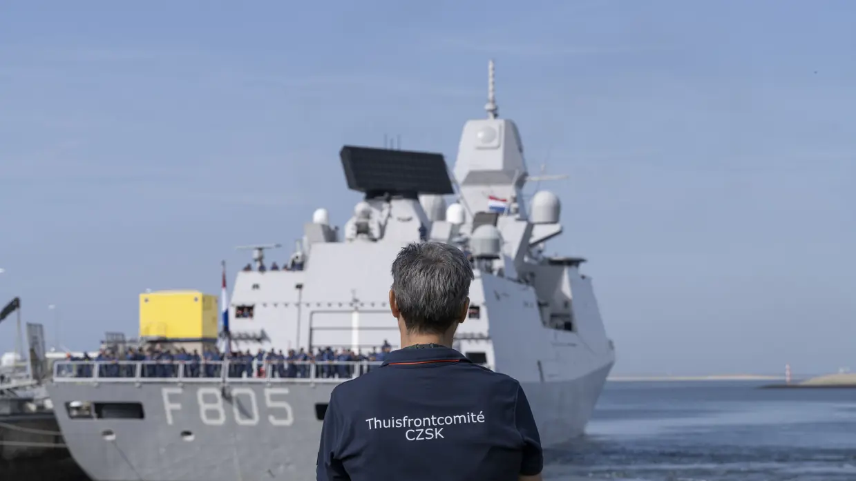 Een man op de rug gezien kijkt naar een uitvarend schip