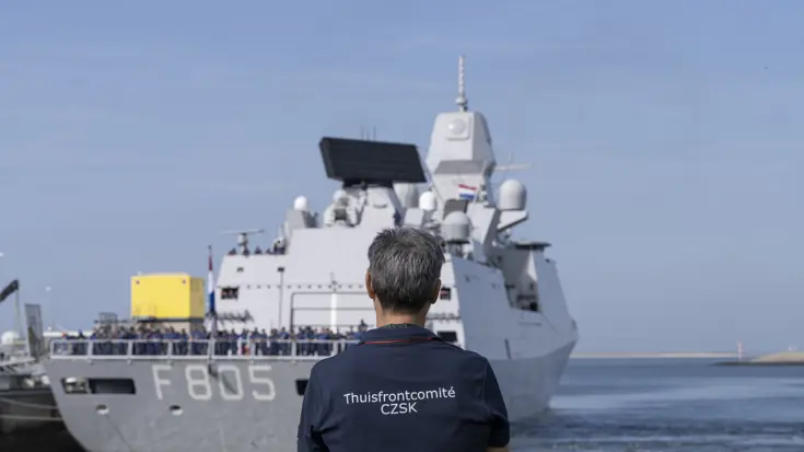 Een man op de rug gezien kijkt naar een uitvarend schip