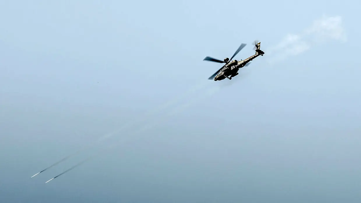 Een Apache duikt naar beneden en vuurt twee raketten af.