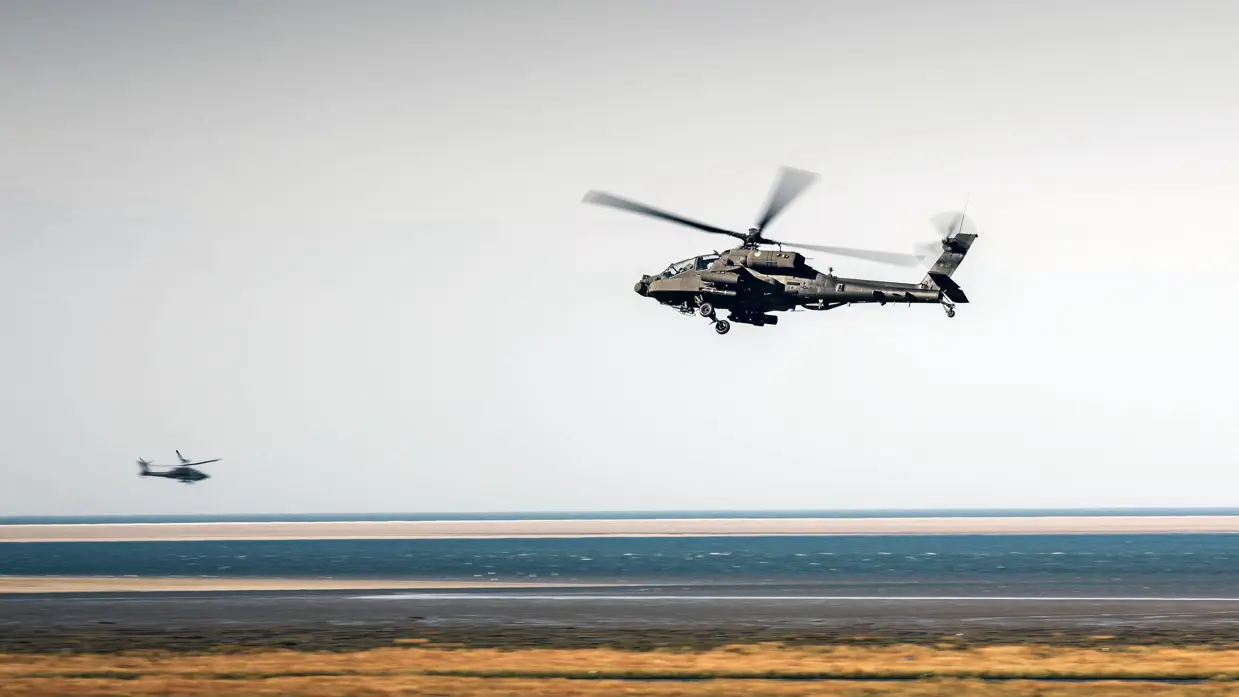 Twee Apaches boven een kaal bruin landschap.