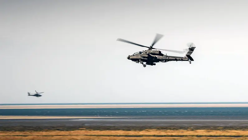 Twee Apaches boven een kaal bruin landschap.