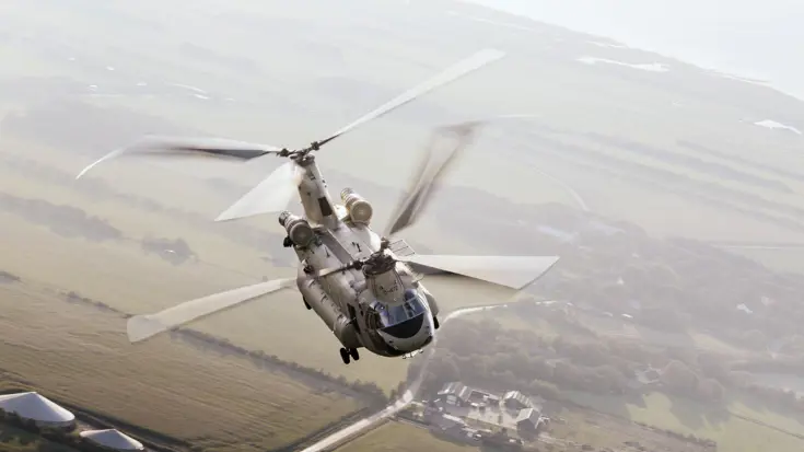 Een Chinook van boven gezien vliegt over een vlak landschap.