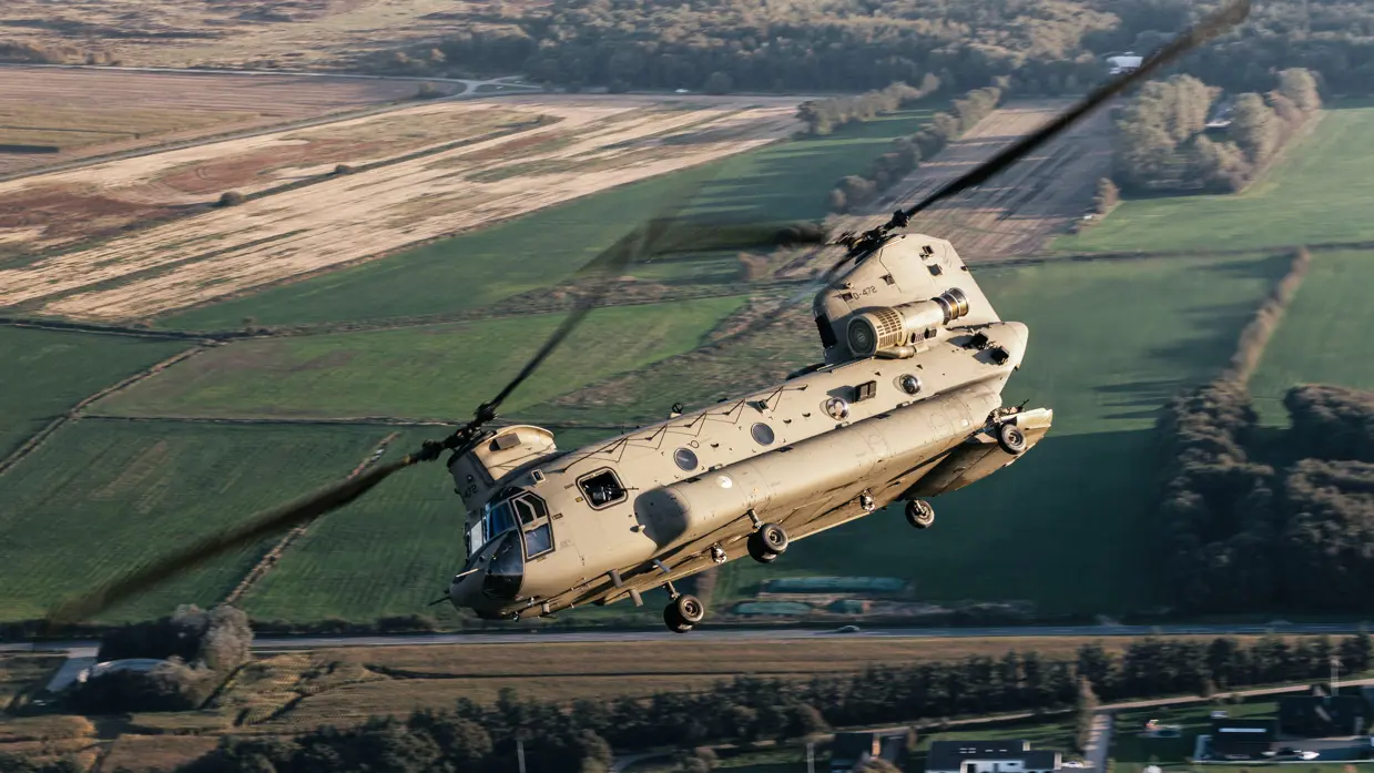 Chinook trekt een bocht boven een landelijk gebied.