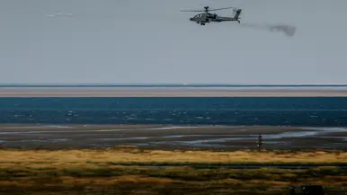 Een zwarte helikopter hangt in de lucht en vuurt twee raketten af.