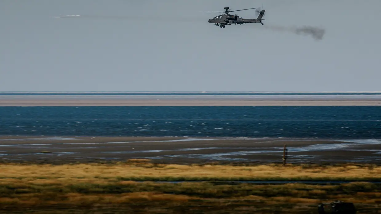 Een zwarte helikopter hangt in de lucht en vuurt twee raketten af.